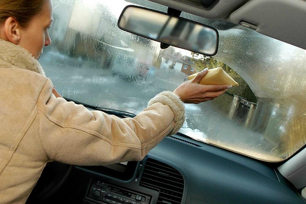Девушка протирает запотевшие стекла автомобиля
